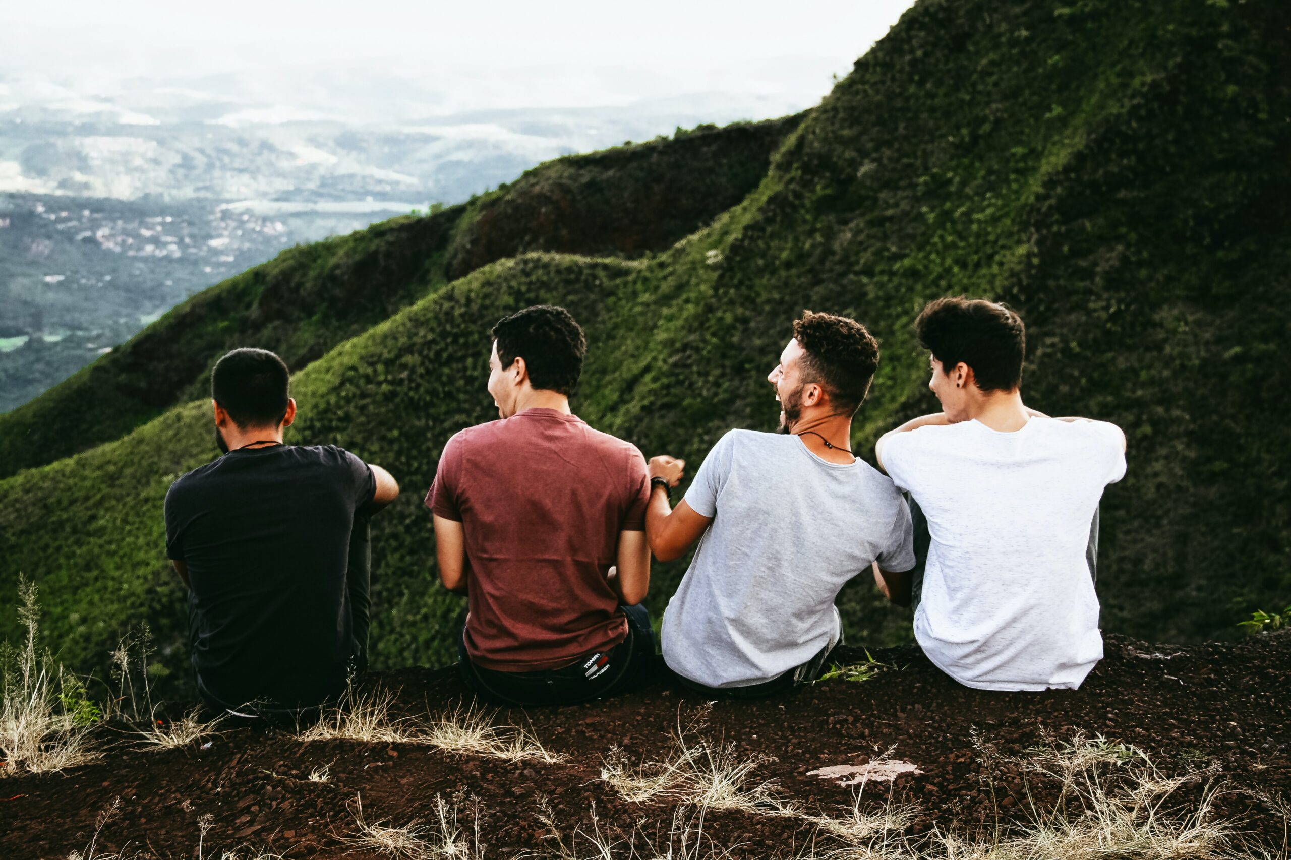 Gruppe von Männern sitzen an einer Klippe mit wunderschöner Aussicht